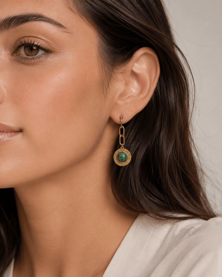 Green stone drop earrings worn on the ear